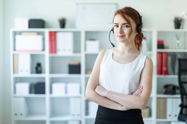 Beautiful young girl in headphones with microphone standing in office. - Fotoğraf, Görsel