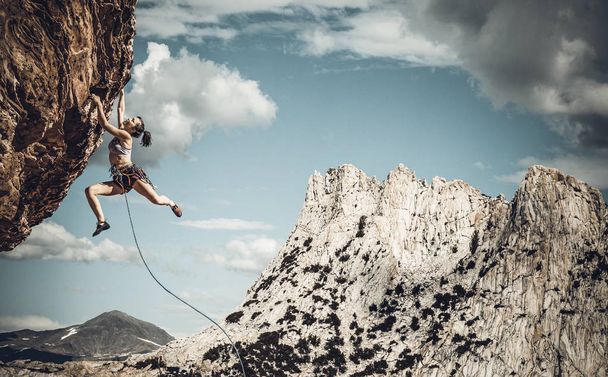 Female climber struggeling up a sheer cliff. - Photo, Image