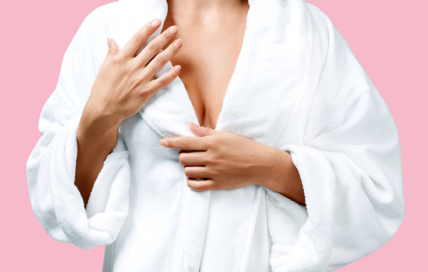 Body care concept. Beautiful woman after bath in white bathrobe on pink background. - Photo, Image