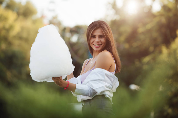 Smiling woman holding big cotton candy in a park - Фото, изображение