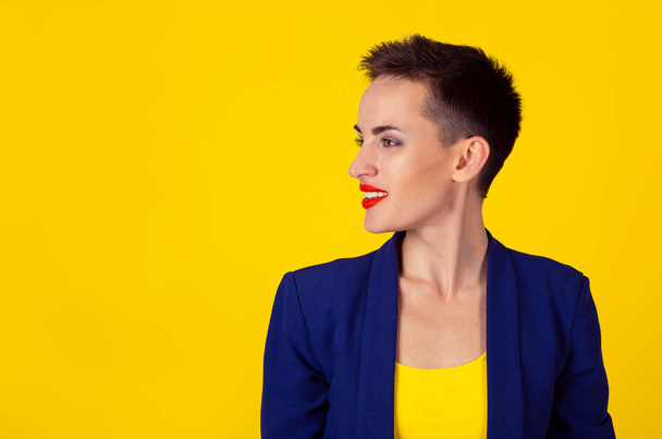 Portrait of a pretty happy woman in profile looking to the right side smiling toothy about to say, saying something isolated on yellow wall background  - Photo, Image