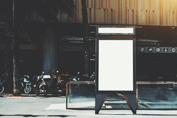 Вертикальный пустой шаблон плаката на улице с мотоциклами и метро или подземным входом сзади; чистый рекламный макет баннера в городских условиях в летний день
 - Фото, изображение