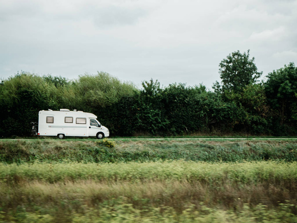 Autocaravana blanca RV Camping van de conducción rápida - autocaravana de conducción en verde ambiente ecológico limpio para el tiempo de recreación camping
 - Foto, Imagen