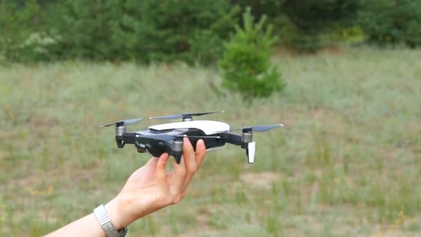 Una mano de hombre sostiene un dron o cuadrocoptero contra el fondo de un bosque verde. Tecnologías futuras
 - Metraje, vídeo