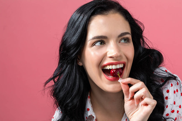 Happy young woman holding a cherry - Фото, изображение