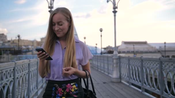 Молода бізнес-леді ходить по мосту з телефоном
 - Кадри, відео