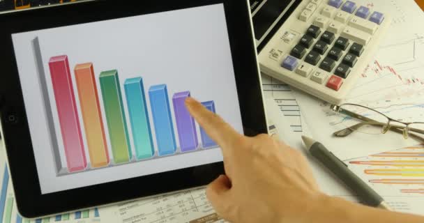 Homme d'affaires travaillant sur la tablette avec des diagrammes, doigt touchant les graphiques à secteurs du marché financier Graphique à l'écran de l'ordinateur, document de rapport d'analyse d'entreprise & calculatrice sur la table
. - Séquence, vidéo