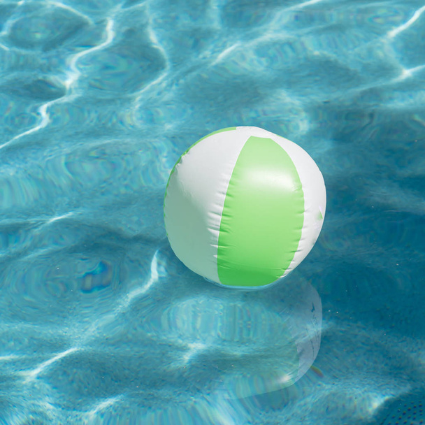 Bir parlak yeşil yaz güneşte yansıtan dalgalar ile yüzme havuzu yenileme içinde yüzen Wasserball mavi yüzme havuzunda. Aktif bir tatil arka plan. Çocuk için hayatımı kurtardın. Güneşli bir gün havuz başında - Fotoğraf, Görsel