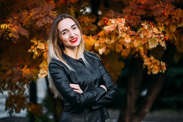 young happy woman in a black leather jacket looks into the camera - Fotografie, Obrázek