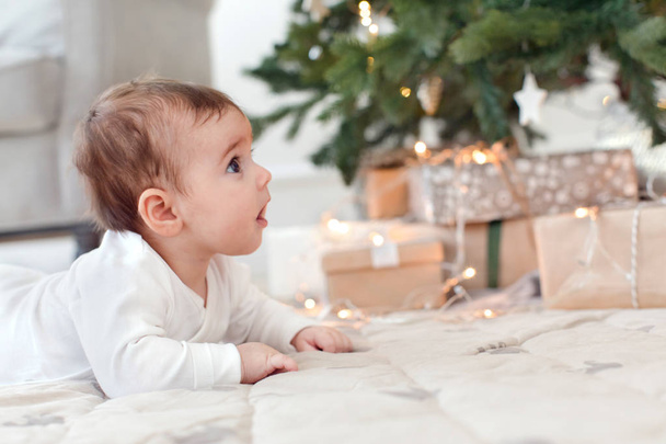 Curious little infant baby under Christmas tree - Foto, afbeelding