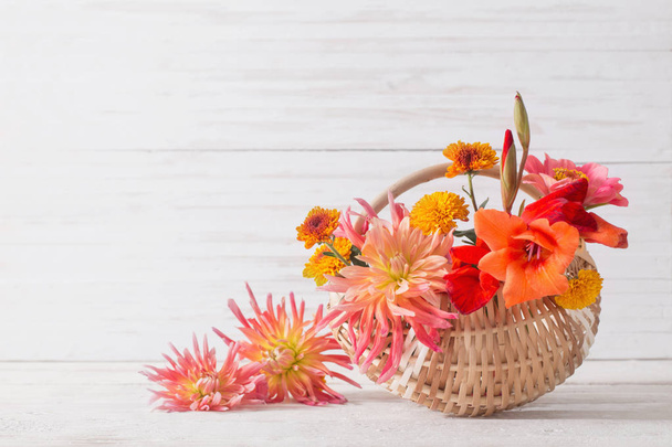 summer flowers in basket on wooden table - Foto, afbeelding