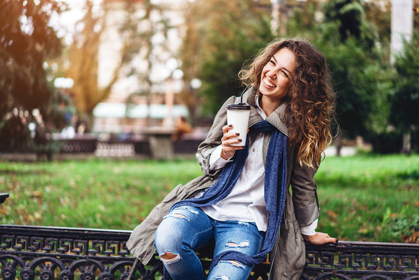 girl with curly hair holding coffee cup and smiling - Foto, Bild