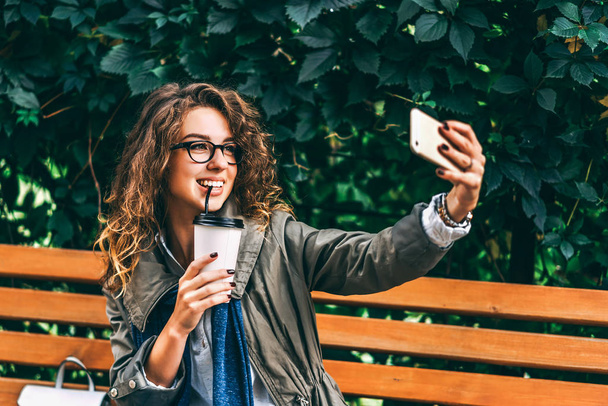 girl with curly hair taking selfie with coffee cup - Фото, изображение