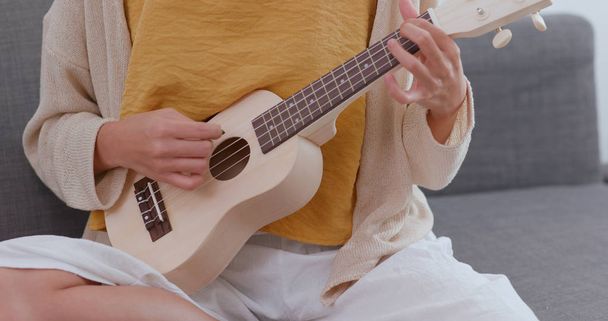 Woman playing song with ukulele at home - Fotó, kép
