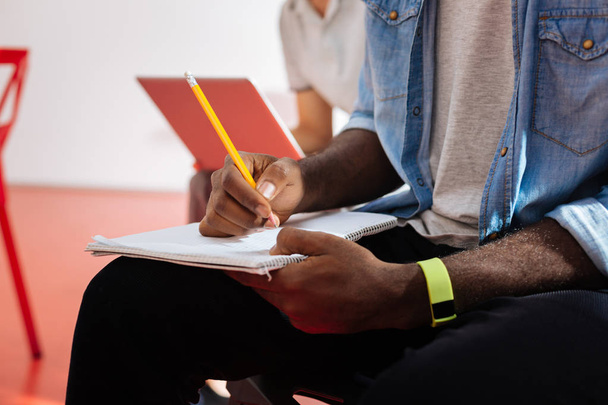 Close up of black man making notes in his notebook - Photo, image