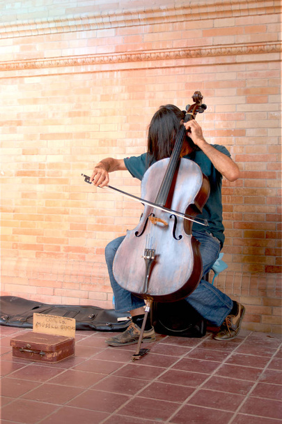 A street musician with long hair plays the double bass. - Photo, Image