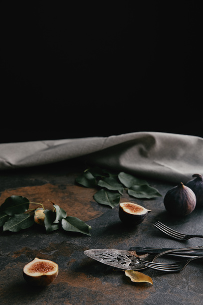 close up view of antique cutlery, green leaves and figs on grungy surface - Foto, immagini