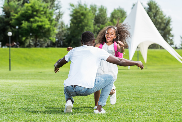 africano americano colegiala corriendo a padre con abierto brazos en parque
 - Foto, imagen