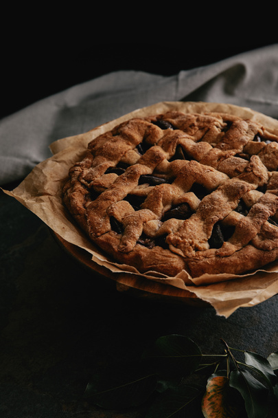 close up view of homemade pie on baking paper on dark background - Zdjęcie, obraz