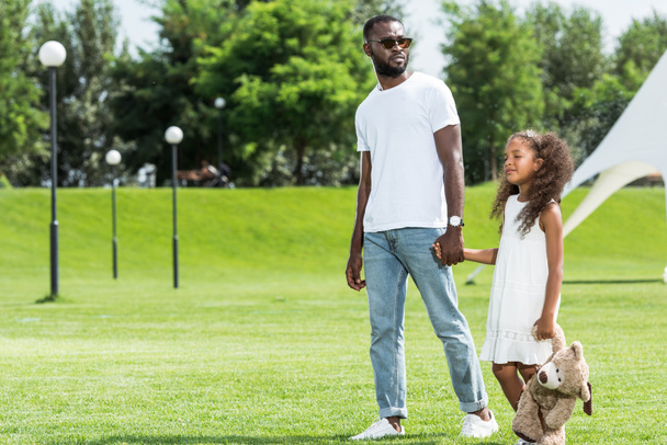 afro-americanos padre e hija tomados de la mano y caminando en parque
 - Foto, imagen