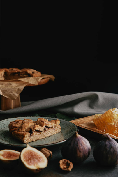 close up view of baked pie, beeswax and figs arranged on dark surface  - Фото, изображение