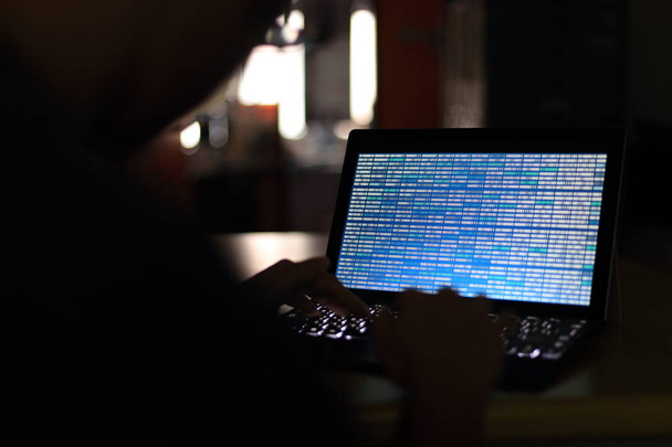 Silhouette de pirate informatique tapant sur l'ordinateur dans une pièce sombre. Je travaille sur la technologie du code binaire bleu. données binaires, programmation informatique et concepts de sécurité réseau
. - Photo, image