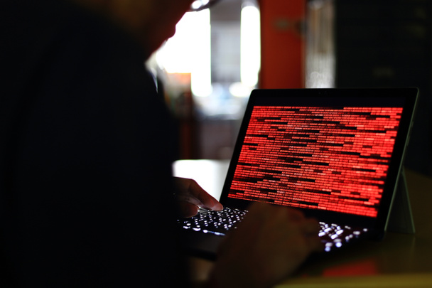 Ηλεκτρονικό έγκλημα σιλουέτα Hacker πληκτρολογήσετε στον υπολογιστή σε ένα σκοτεινό δωμάτιο. Εργάζεται πάνω σε τεχνολογία δυαδικό κώδικα. δυαδική έννοιες ασφάλειας δεδομένων, ηλεκτρονικό έγκλημα και δικτύου. - Φωτογραφία, εικόνα