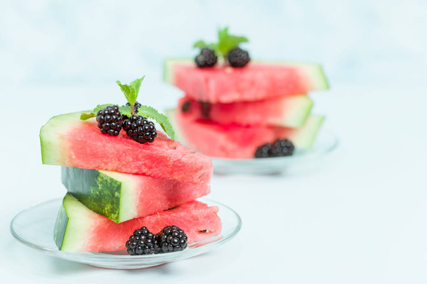 Watermelon sliced pie with blackberries and mint leaf on blue pastel background with copy space - close up macro photography of summer fresh raw ripe fruit for delicious vegetarian dessert. - Foto, Bild