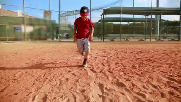 Disparo en cámara lenta del niño corriendo hacia la primera base y deslizándose en el parque de béisbol. El chico corre hacia la cámara
. - Metraje, vídeo