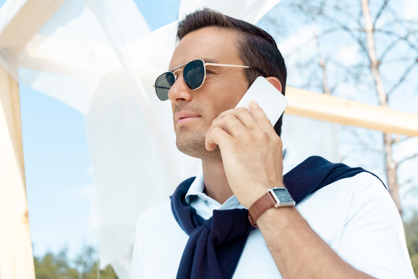 portret przystojny mężczyzna okulary rozmowy na smartphone z niebieskiego nieba deszczu na tle - Zdjęcie, obraz
