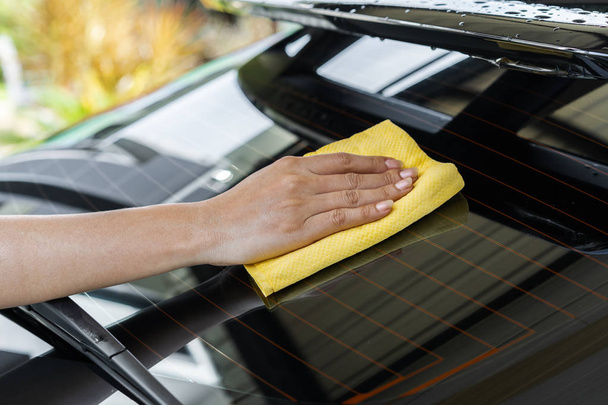 hand with a microfiber cloth cleaning the rear window of a car - Foto, Imagen