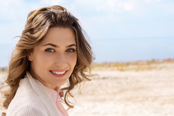 retrato de la mujer sonriente mirando a la cámara en la playa de arena
 - Foto, Imagen