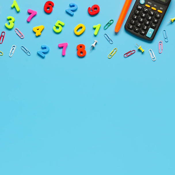 Kalkulator, pióra, kolorowe numery na niebieskim tle. Kopiowanie kompozycji przestrzeni - Zdjęcie, obraz