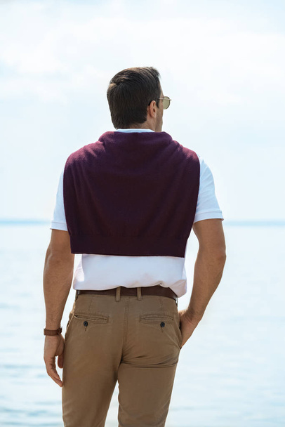 rear view of man standing and looking at river on summer day - Photo, Image