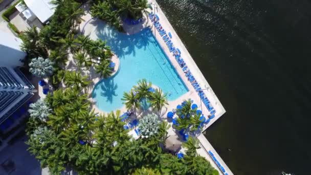 Aerial shot over pool area of building located next to a waterway in Miami - Felvétel, videó
