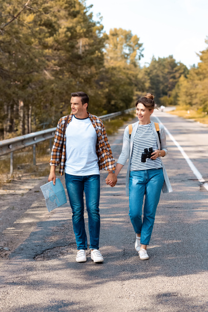 couple with backpacks holding hands while traveling together - Photo, Image