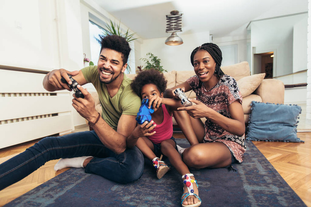 Familia sonriente sentada en el sofá jugando videojuegos
 - Foto, imagen