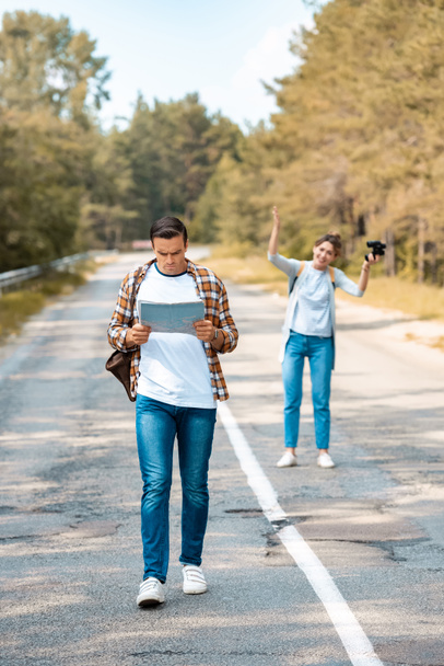 selective focus of man with map and girlfriend with binoculars behind on road - Photo, Image