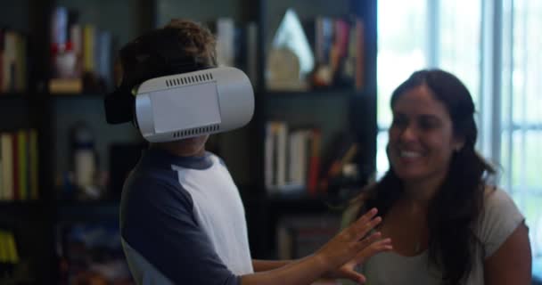 Slow Motion toma de un niño jugando con su gafas VR mientras su madre mira y sonríe
 - Metraje, vídeo