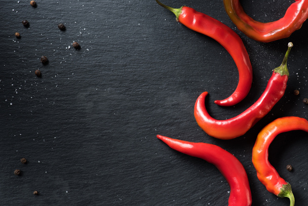 elevated view of red organic chili peppers on black surface - Foto, immagini