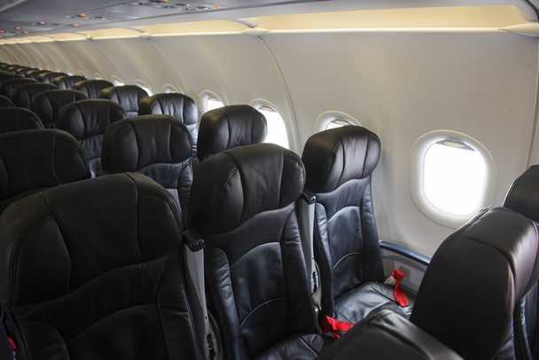 leere Sitze und Fenster in der Economy Class aus schwarzem Leder - Foto, Bild