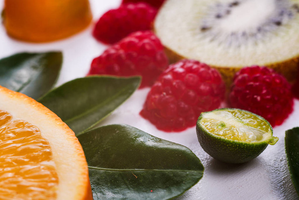 Close-up of flowers made of juicy citrus fruits isolated on white. Orange, lemon, kiwi, mandarin and raspberry. Colorful and fresh composition. Fruits pattern. - Photo, Image