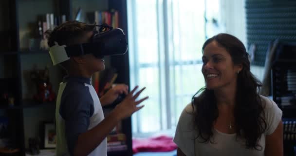 Slow Motion shot of a woman smiling as she watches her son play with VR goggles/headset - Footage, Video