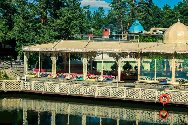 Het restaurant en de begroeide kust worden weerspiegeld in de spiegelend oppervlak van het meer in de herfst park. - Foto, afbeelding