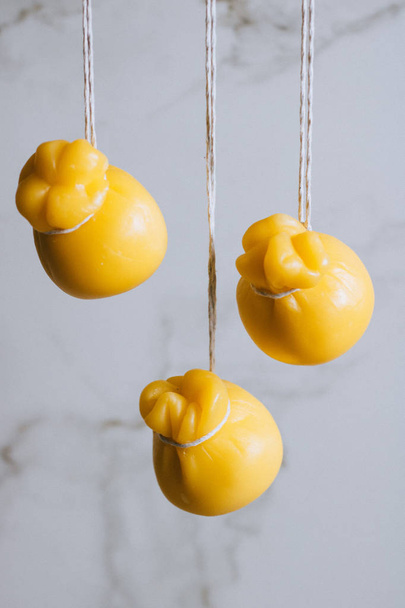 Scamorza cheeses are hanged together in strings to ripen on marble background - Photo, Image