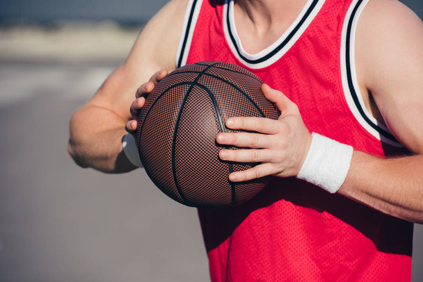 περικομμένη εικόνα του αθλητή που παίζει μπάσκετ στην οδό - Φωτογραφία, εικόνα