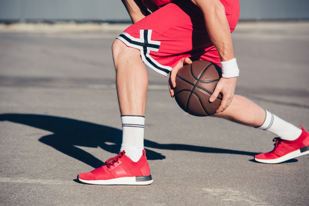cropped image of basketball player playing basketball on street - Photo, Image