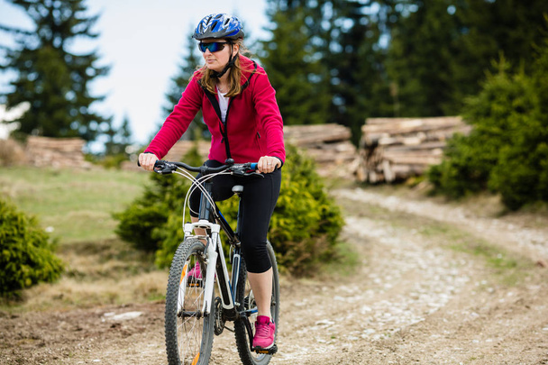 Woman in sportswear riding bicycle in field. - Foto, Imagen