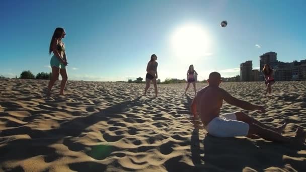 The company of young sports people playing beach volleyball, one of the players gets up from the sand after the fall - Footage, Video