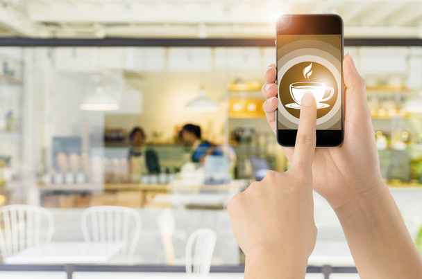 Touch screen smart phone on coffee icon with blurred coffee shop background. Concept Food online. - Photo, Image